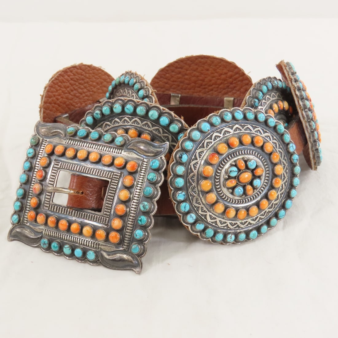 Gary Reeves Navajo Sterling Concho Belt: Gary Reeves Navajo Sterling Concho Belt - sterling silver hand stamped square buckle, 8 oval conchos with turquoise & coral cabochons, on 48" leather belt weighs 1 lb 12.7 oz total weight. Lot