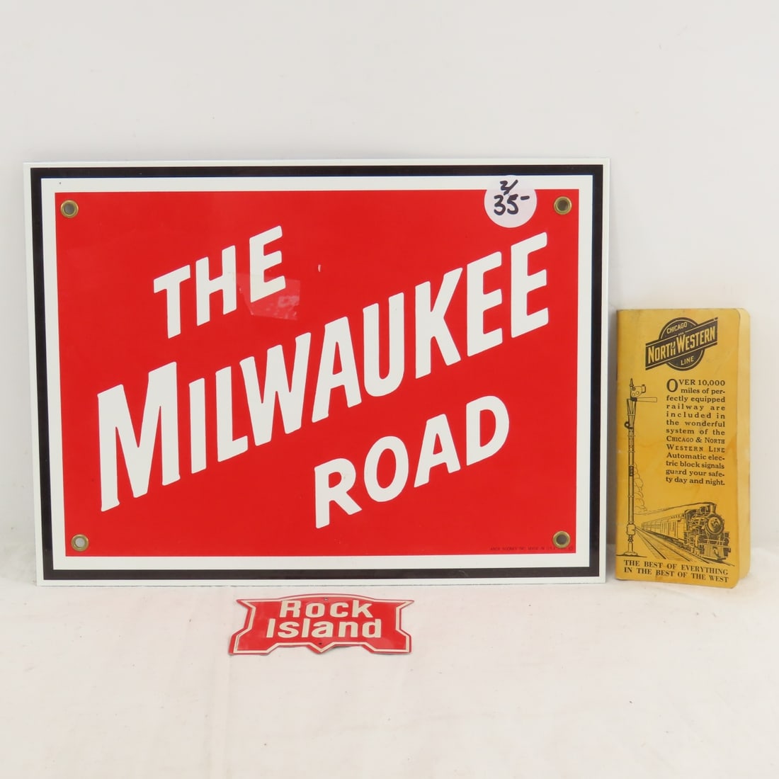 Reproduction Milwaukee Road & Rock Island RR Sign: Reproduction Milwaukee Road & Rock Island RR Sign - Ande Rooney Reproduction Milwaukee Road Enamel Sign 11 x 8", Rock Island Mini Sign, 3.5 x 2.5", Chicago Northwestern Pocket Notepad. Lot Size: