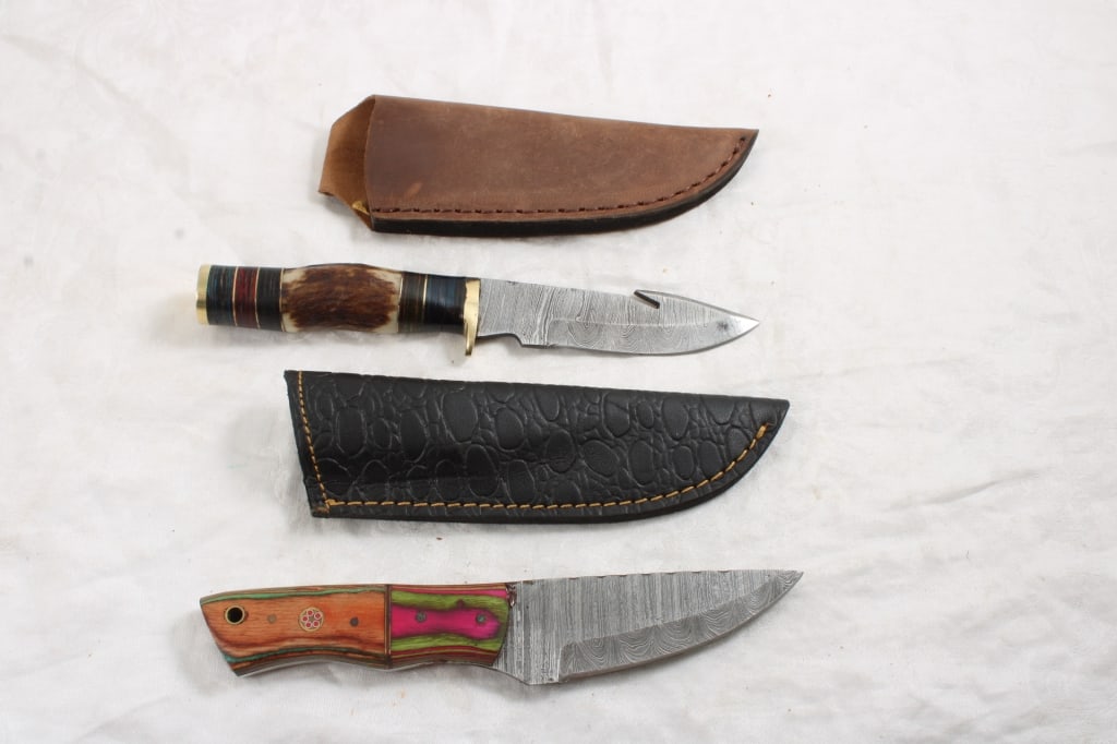 2 Fixed Blade Damascus Custom Made Knives: 2 Fixed Blade Damascus Custom Made Knives - with Sheaths. One with Gut Hook. Lot Size 10" x 5" x 3". 1 Lb. Photos are part of description (Live Auctioneers on displays a max of 20 photos -check
