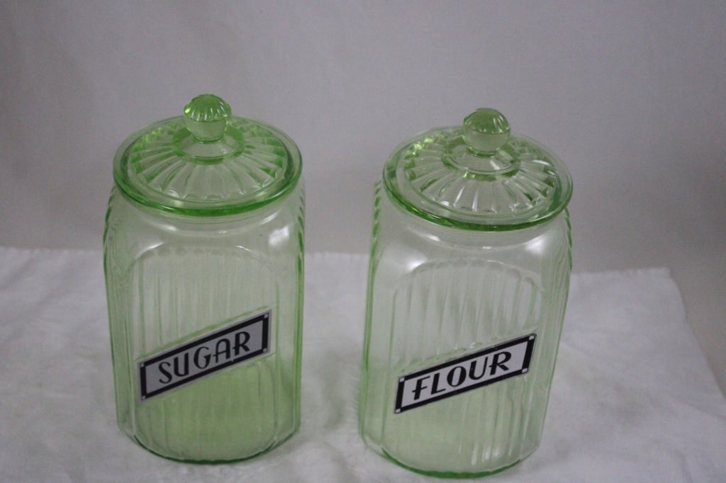 2 Green Uranium Glass Ribbed Canisters -Glows: 2 Green Uranium Glass Ribbed Canisters -Glows - 2 Anchor Hocking Green Uranium Glass Ribbed Canisters Sugar and Flour 9" Tall. Both have tiny flea bites on inner rims of the jars. Lot Size