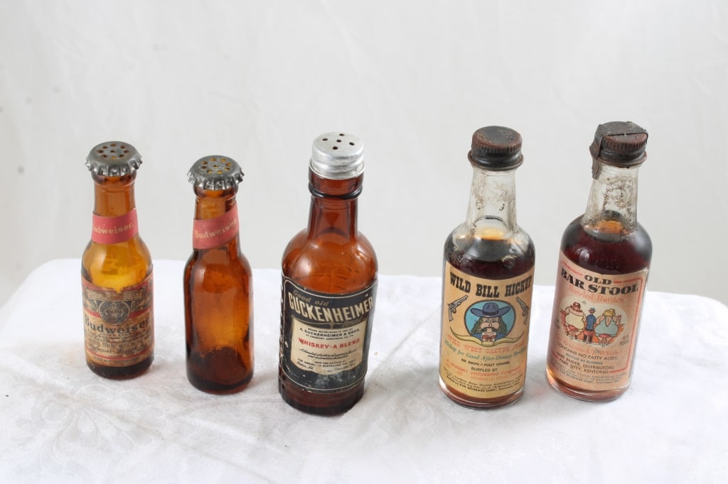 3 Mini Whiskey Bottles, 2 Budweiser Shaker Bottles: 3 Mini Whiskey Bottles, 2 Budweiser Shaker Bottles - Guckenheimer Whiskey w/Shaker Lid, 2 Budweiser Mini Shaker Bottles, Old Bar Stool Whiskey Bottle, Wild Bill Hickok Cactus Juice Bottle. Lot Size 5"