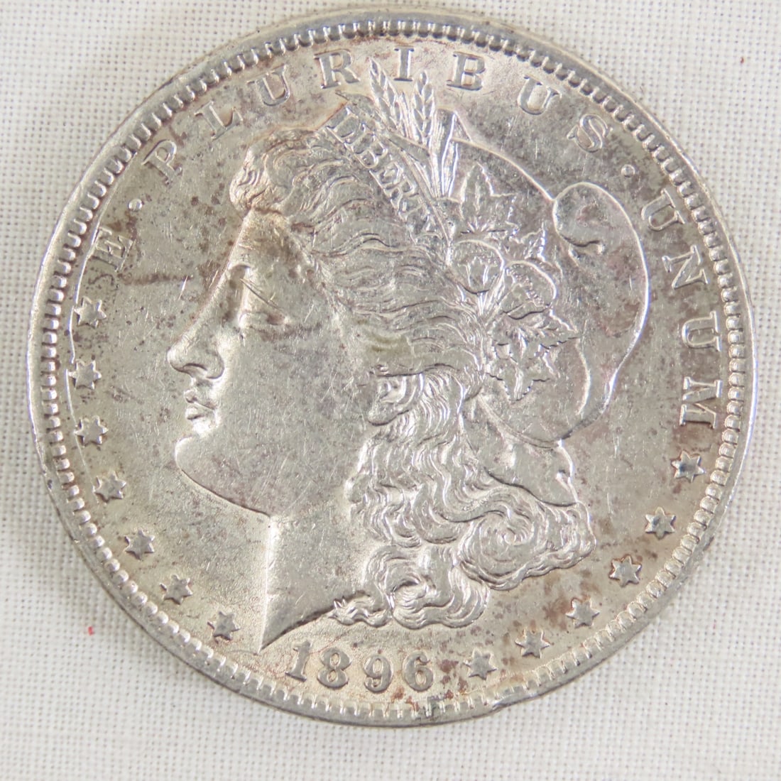 1896 Morgan Silver Dollar: 1896 Morgan Silver Dollar - Lot Size 2x2x1" 1 LB All information and photos are intended to be as accurate as possible, but errors are possible. No item may be returned or refused based on this