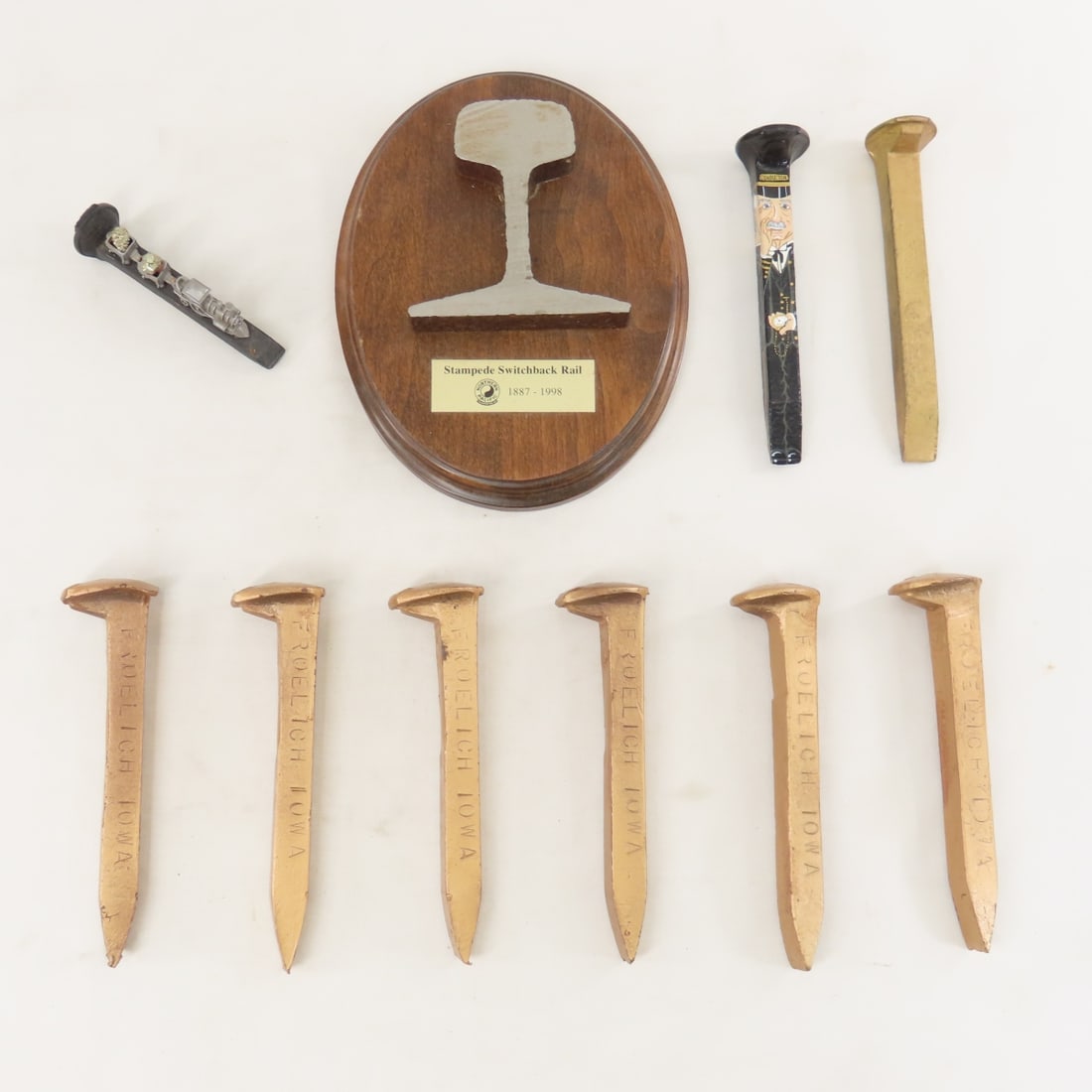 NP Switchback Rail Section, Spikes & More: NP Switchback Rail Section, Spikes & More - 6 golden spikes from Froelich, Iowa, 1 unnamed, 1 conductor painted, 1 smaller with pewter train, 1187-1998 Stampede Switchback Rail section plaque. LOT