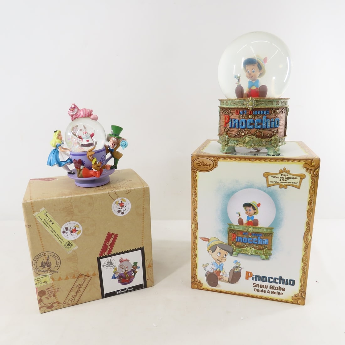 Disney Alice Tea Cup & Pinocchio Snow Globes: Disney Alice Tea Cup & Pinocchio Snow Globes - Disney Parks Alice Tea Cup Snow Globe and Disney Store Musical Pinocchio Snow Globe- plays "When you wish upon a star"- both in boxes. LOT SIZE: 12x10x8"