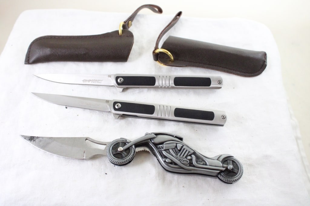 3 Folding Knives- Motorcycle Figural & 2 OHMONEY: 3 Folding Knives- Motorcycle Figural & 2 OHMONEY - OHMONEY Knives are in Sheaths. Lot Size 6" x 4" x 2". 1 Lb. All information and photos are intended to be as accurate as possible, but errors