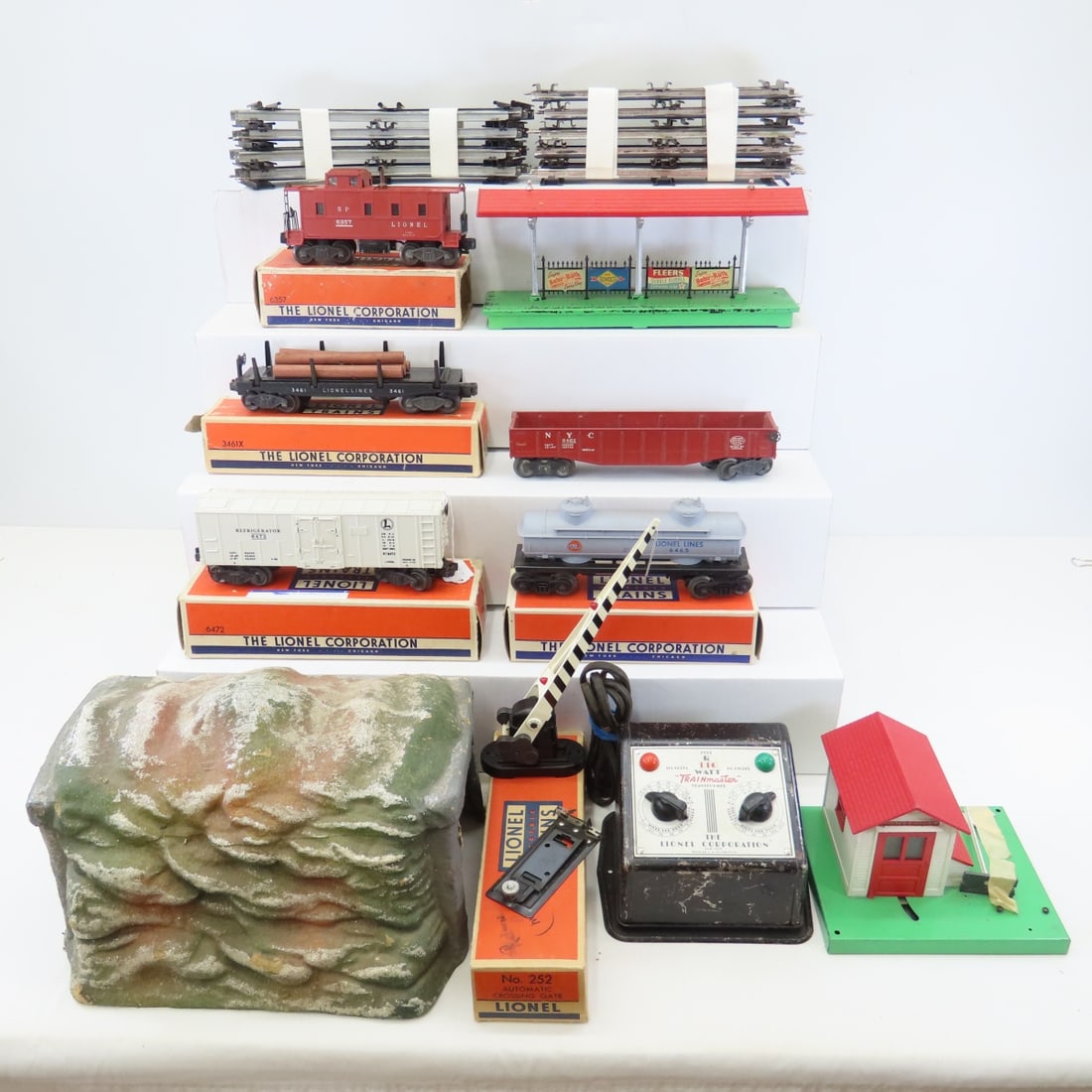 Vintage Lionel O Gauge Lumber, Caboose, Other Cars: Vintage Lionel O Gauge Lumber, Caboose, Other Cars - 6472 Refrigerator Car, 6465-60 Tank Car, 6357 Caboose, 3461X Automatic Lumber Car, Crossing Gate, Track, Transformer, Tunnel. LOT SIZE: 18x18x16" 2