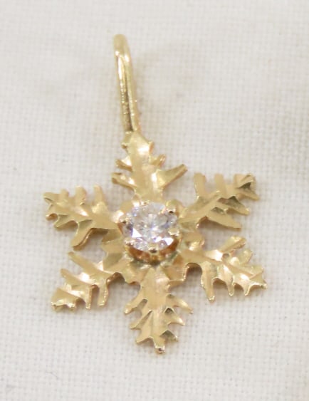 14kt Yellow Gold Snowflake Pendant w/ 3pt Diamond: 14kt Yellow Gold Snowflake Pendant w/ 3pt Diamond - marked IWC 14kt, .9 grams, LOT SIZE: 4x4x4" , .5 LBS All information and photos, which are part of the description, are intended to be as accurate