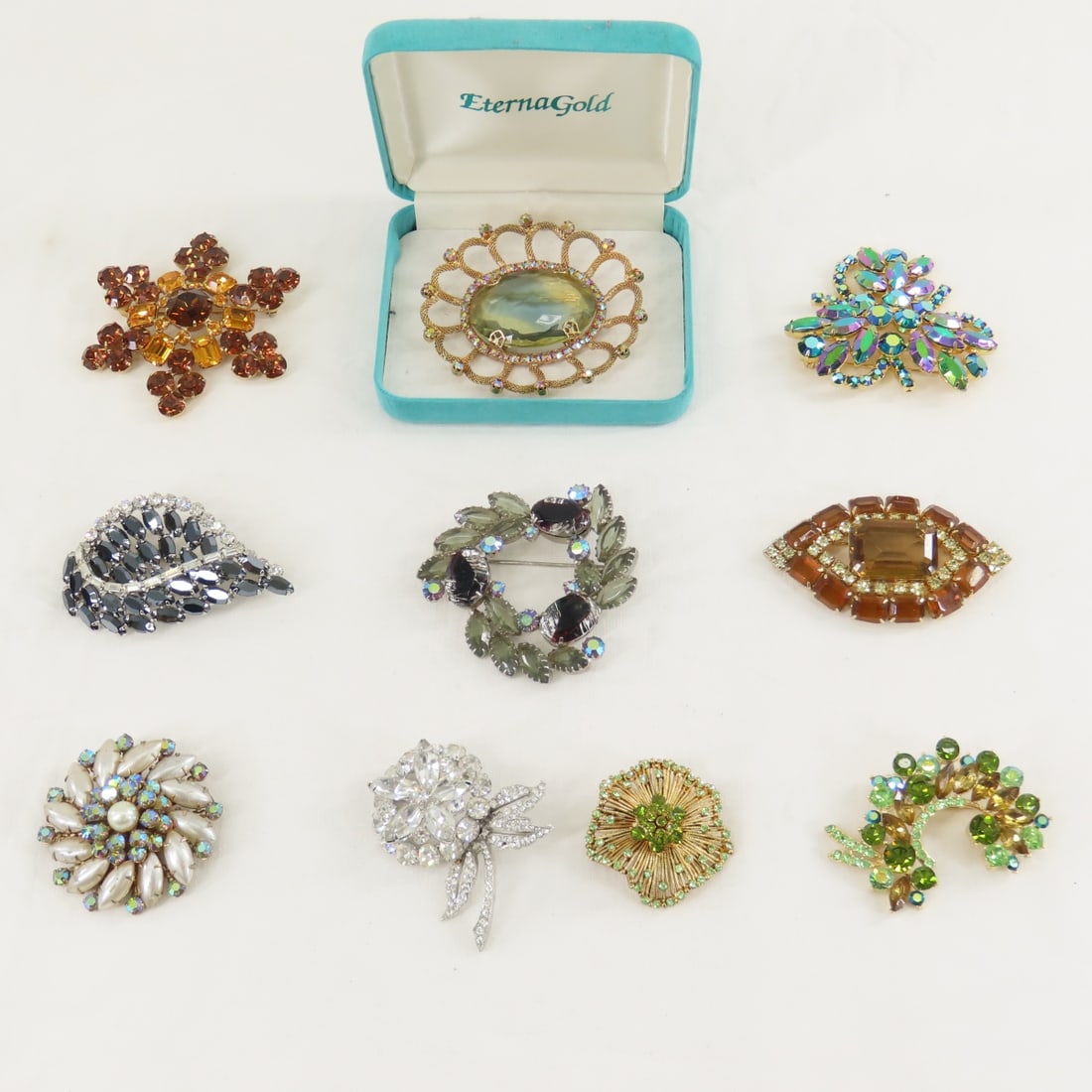 10 Vintage Rhinestone Brooches: 10 Vintage Rhinestone Brooches - large brooch with center ombre stone came in Eterna Gold clamshell but can not verify it is Eterna. All clear stone brooch is missing 1 small stone otherwise all are
