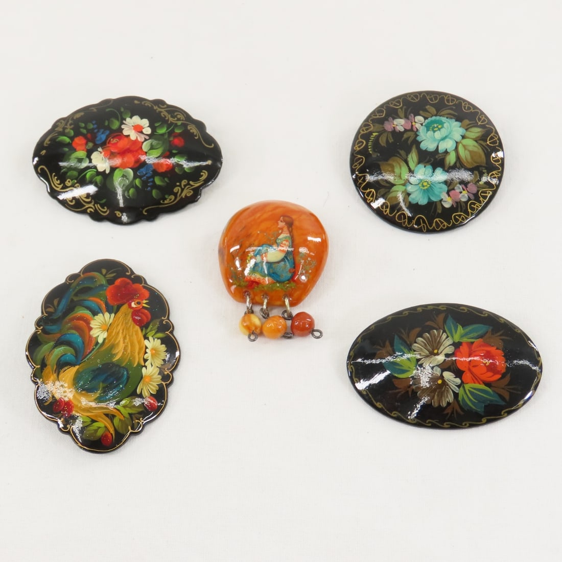 5 Handpainted Russian Lacquer Brooches: 5 Handpainted Russian Lacquer Brooches - 4 black ones are signed. LOT SIZE: 6x6x1" 1 LB All information and photos, which are part of the description, are intended to be as accurate as possible, but