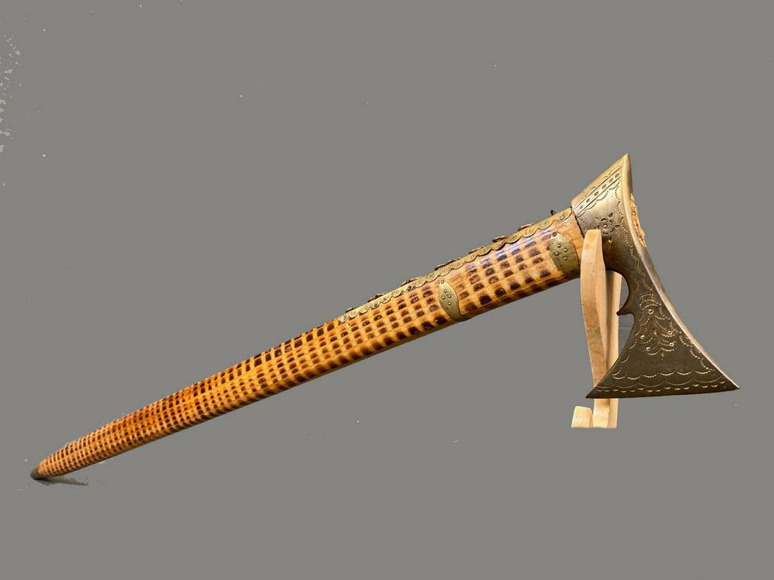 Polish Ceremonial Shepherd's Axe, 20th C.: Polish Brass, pyrography wood, And Steel Tip Axe. Axe head is engraved with brass rings down burnished wood shaft ending with steel point at hilt. Approximately 33.5 x 5.5 x .75in.