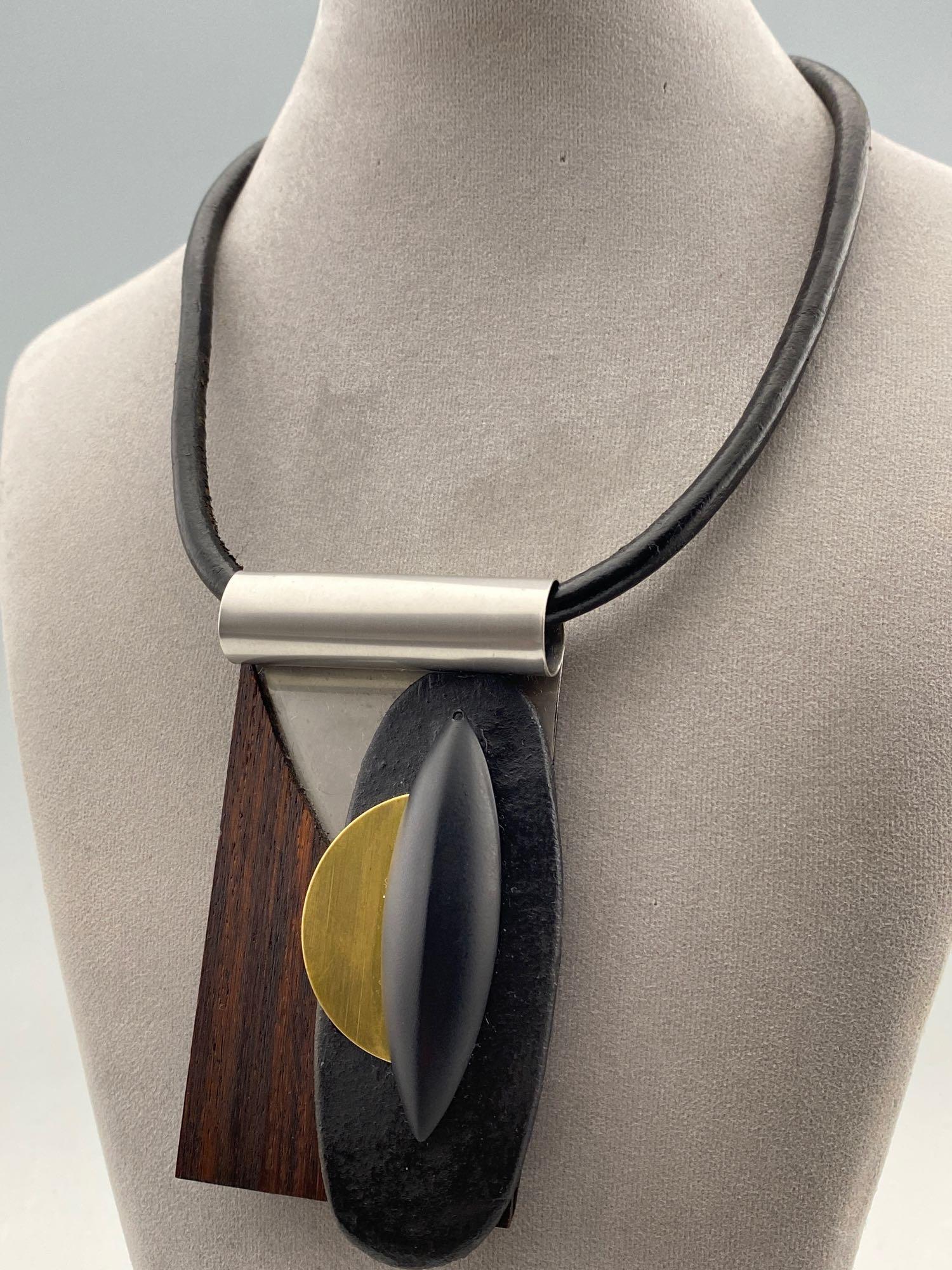 Shirley Wagner Modernist Pendant on Black Leather: Shirley Wagner Modernist Pendant on Black Leather Magnet Clasp signed Shirley Wagner, pendant 3.8125 x 2.1875 inches, chord length 18.5 inches, measurements are approximate. ALL CREDIT CARDS WILL BE M