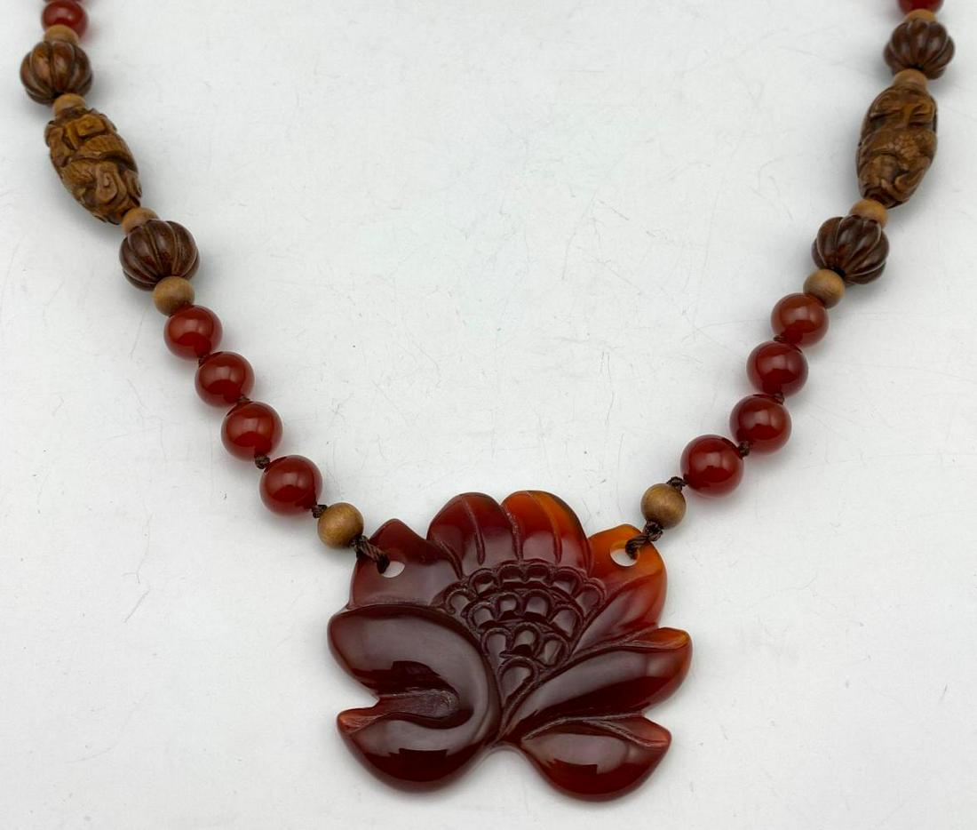 Chinese Necklace of Carnelian Beads, Carved Carnelian: Chinese Necklace of Carnelian Beads, Carved Carnelian Pendant, and Carved Olive or Peach Pit Beads. 95.2 g, approximately 14.625 in. long, largest wooden bead 1.125 x 0.5 in.
