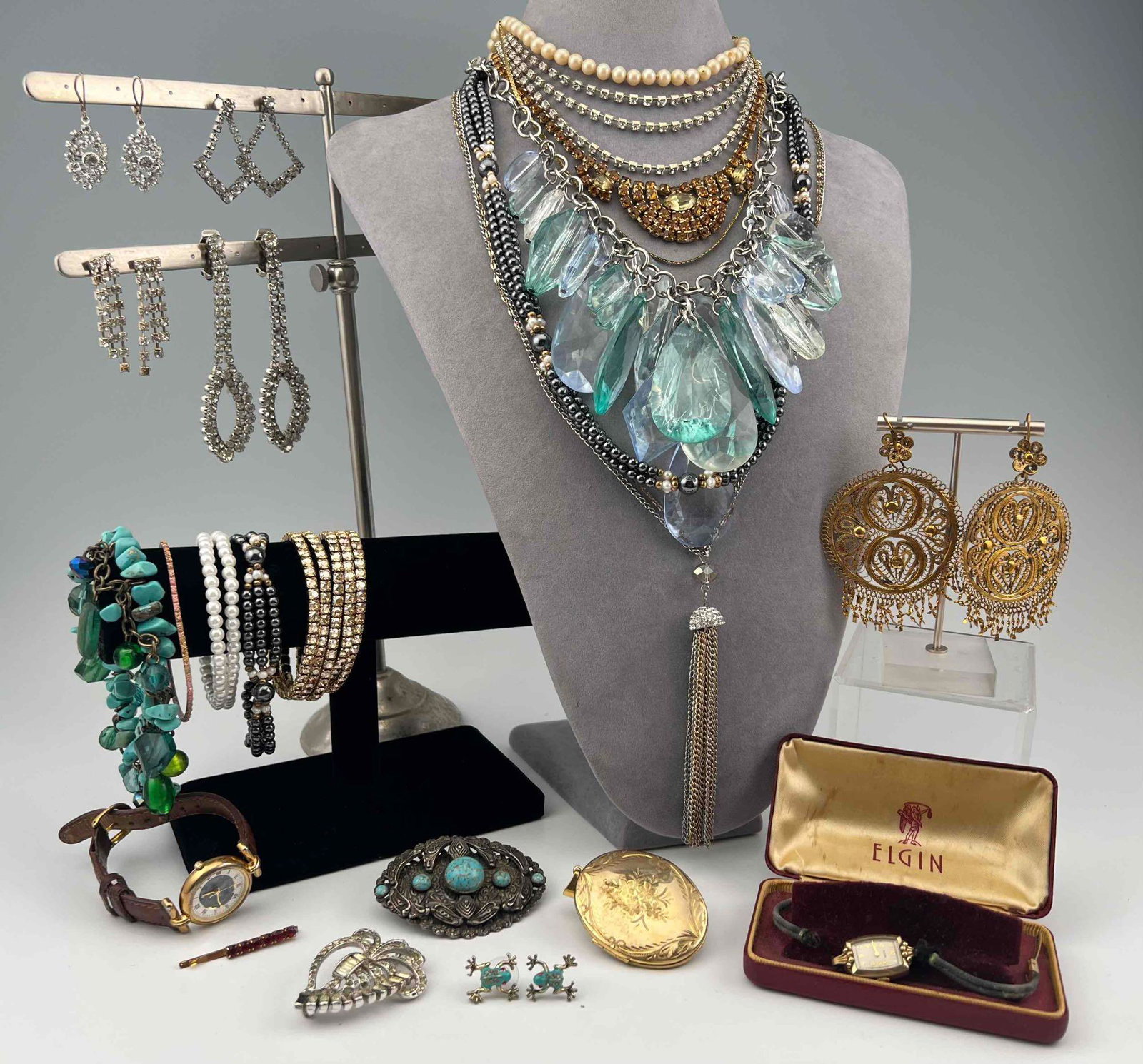 Costume Jewelry Lot: Costume Jewelry Lot. Includes Necklaces, Bracelets, Earrings, Pins, Watch, And Antique Locket. Largest Necklace Approximately 24.75in Long. Smallest Earrings Approximately 0.625L x 0.5W in.