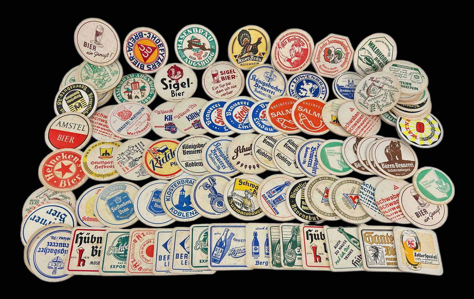 Large Lot of Vintage German Brewery Coasters: 100 Vintage German Brewery Coasters. Largest Approximately 4.25 L x 4.25 W x 0.125 D Inches. Smallest Approximately 3.75 L x 3.75 W x 0.0625 D Inches.