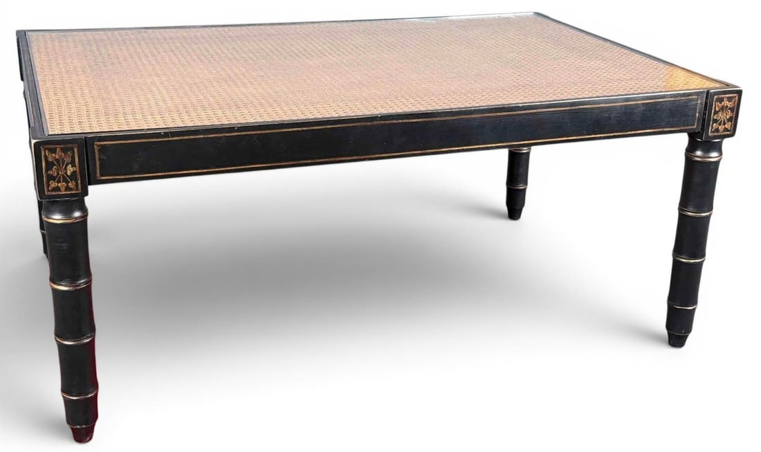 Chinoiserie Cane Top Coffee Table With Gilt Decoration: Rectangular chinoiserie coffee table with woven cane inset top, gilt trim, and gilt floral corner decoration. Raised on turned faux bamboo legs. Approximately 45.87L x 30.0W x 20.12H in.