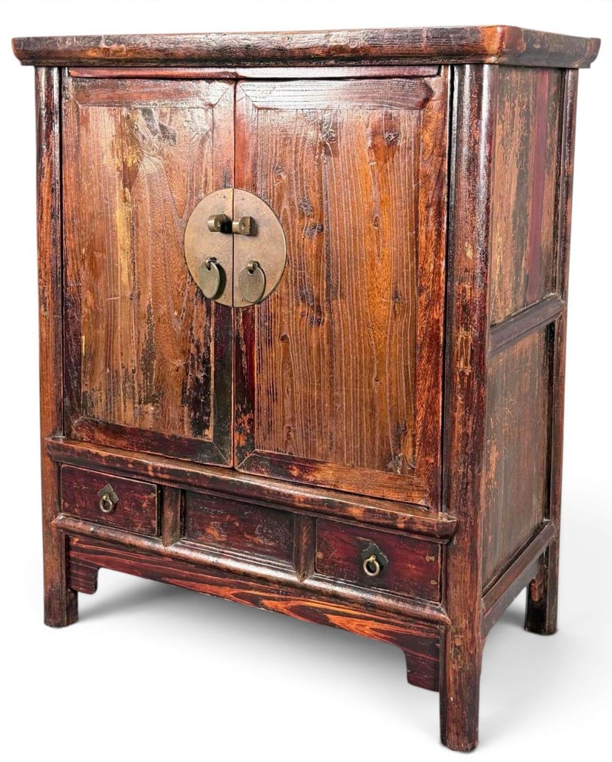 Korean Two Door Cabinet: Small Korean cabinet in a dark reddish-brown finish, with two paneled doors centered by a circular brass lock plate with pulls, opening to a shelved interior with two small drawers. Lower section with