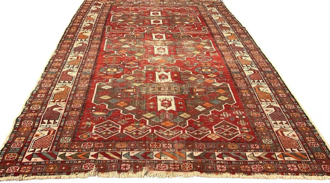 Antique Figural Tribal Rug In The Kazak Tradition: Antique Figural Tribal Rug In The Kazak Tradition. Features geometric medallions in a red field with figural and floral borders. Approximately 6.2L x 3.85W ft. (Approximately 74.5L x 46.25W in.)