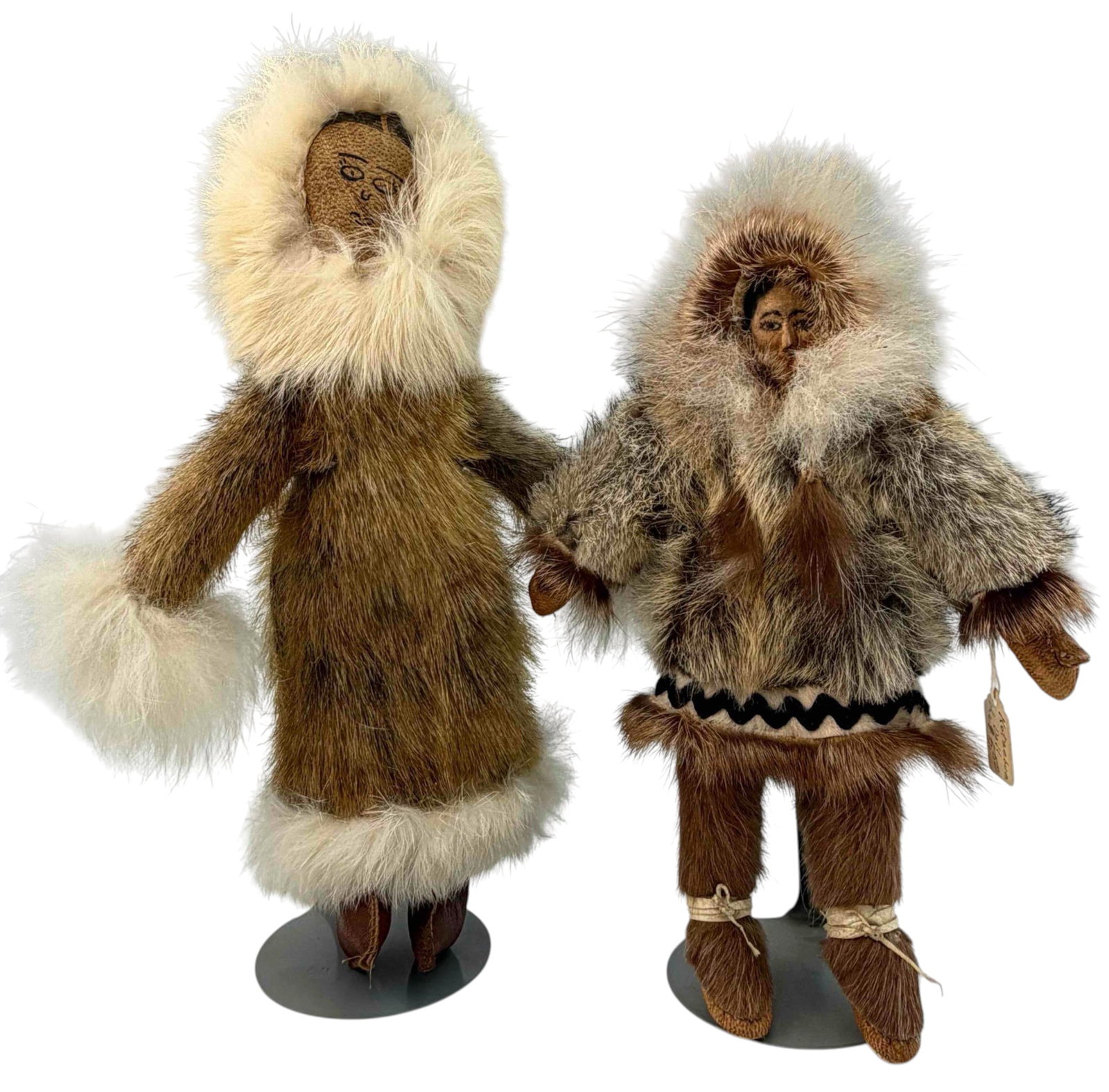 Two Vintage Alaskan Fur-Dressed Dolls: Two Alaskan dolls in traditional-style fur parkas and boots, each with hand-drawn facial features. One doll has a carved wood head and fur outfit with leather boots, and retains a tag marked "Kotzebue