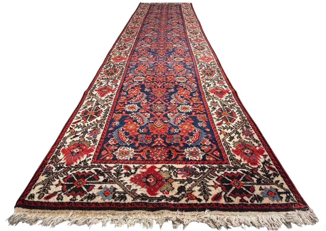 Persian Malayer Runner Rug: Persian Malayer Runner Rug. Hand-knotted wool runner with a dark blue field filled with repeating stylized floral and vine motifs in red, ivory, orange, and blue. Approximately 13.4L x 3.4W ft.