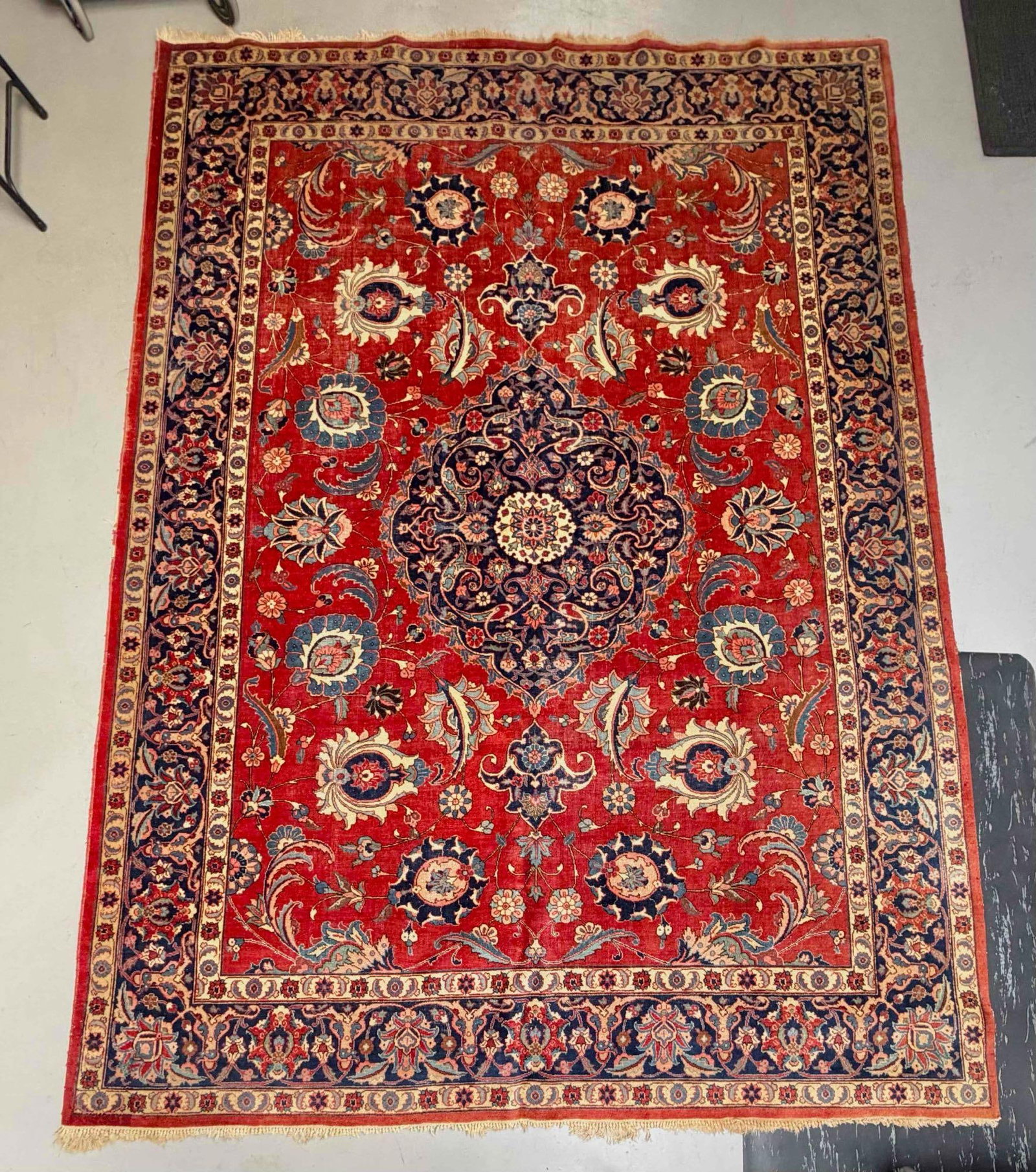 Persian Tabriz Rug: Hand-knotted wool rug with a red field centered by a dark blue floral medallion, surrounded by scrolling vines, palmettes, and stylized floral motifs in blue, ivory, green, and rose tones. Approximate