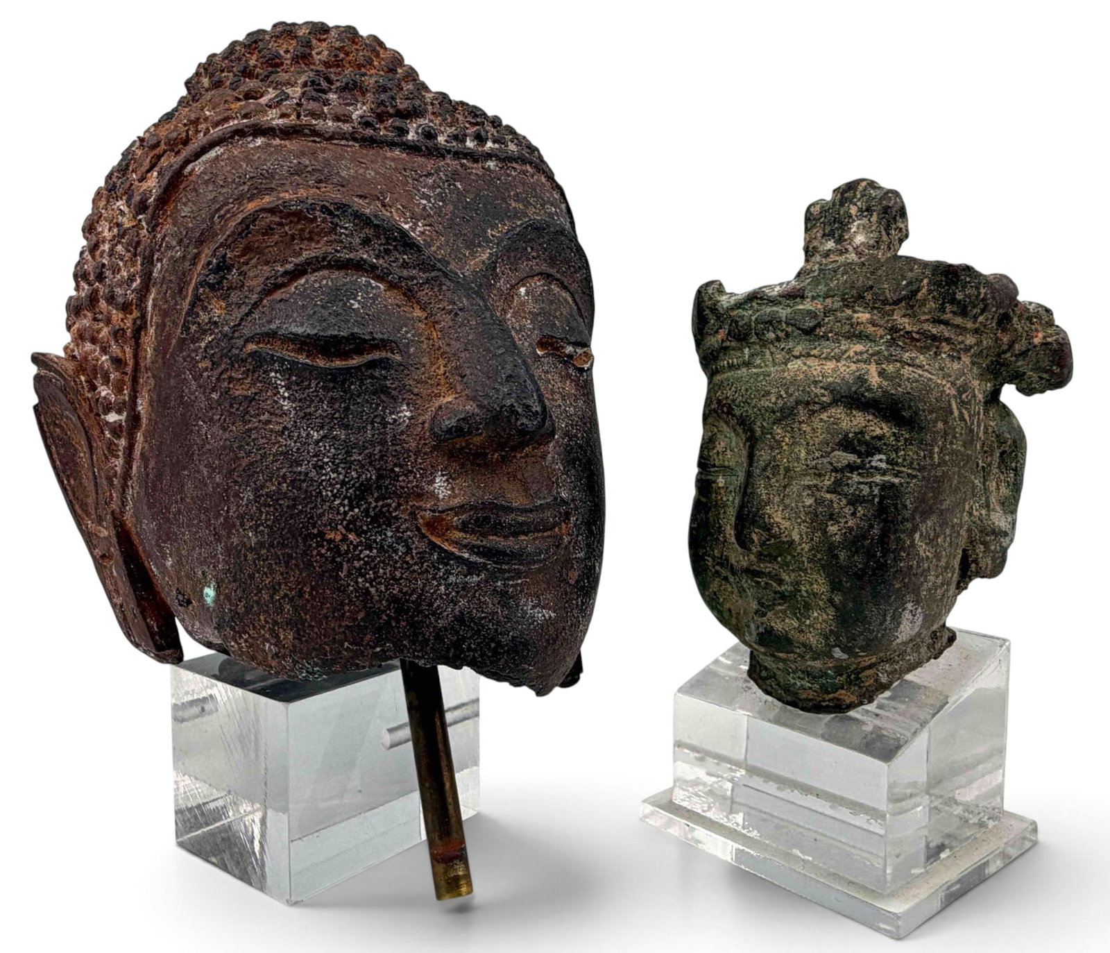 Two Asian Bronze & Iron Buddha Heads: Two Asian Bronze & Iron Buddha Heads. Lager Southeast Asian iron Buddha head approximately 4.0H x 3.17W x 2.80D in. Smaller bronze Buddha head approximately 2.75H x 1.88W x 1.69D in. Height with stand