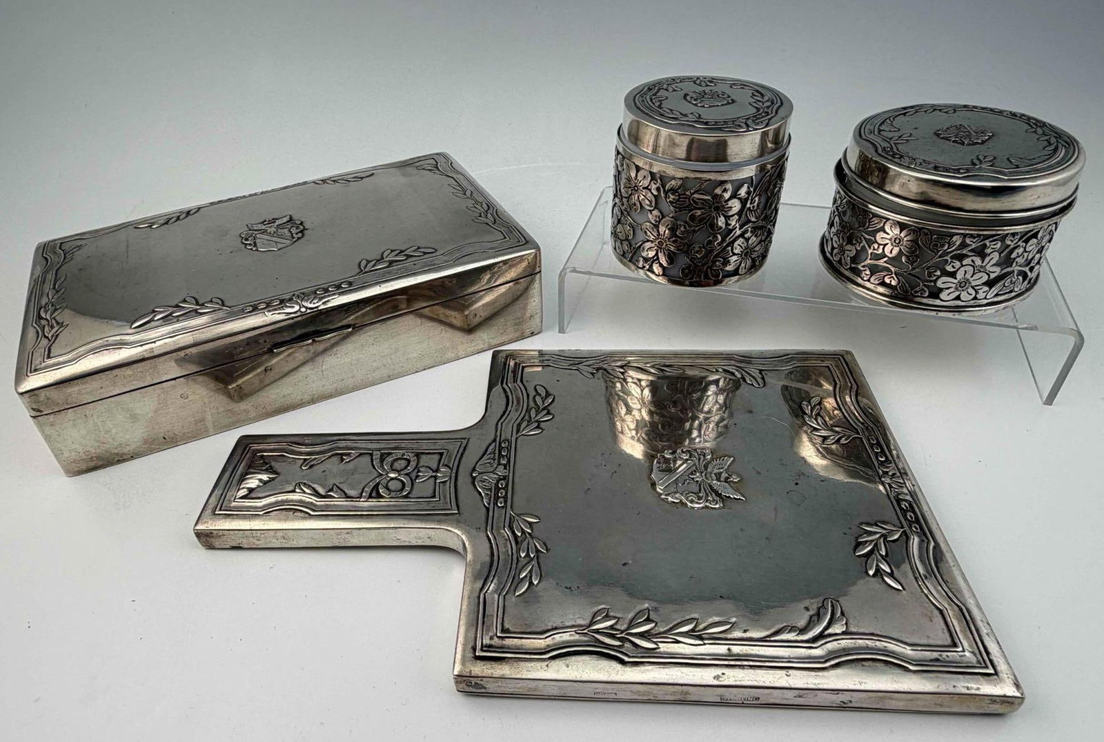 Sterling Silver Vanity Set: Sterling Silver Vanity Set With Coat Of Arms Of The Bulgheroni Family, Ca. 1920. Box and silver jar mounts 767.6g. Mirror 559.7g. Marked "Sterling C.J. Co." Box approximately 7.37L x 4.37W x 1.75H in.
