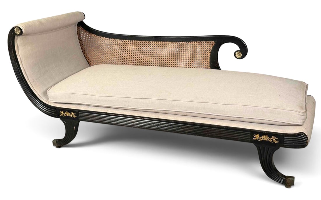 Regency-Style Ebonized And Caned Chaise With Brass Mounts: Regency-style ebonized wood chaise with inset cane panel, and brass rosette mounts. Approximately 69.0L x 33.75H x 27.0W in.