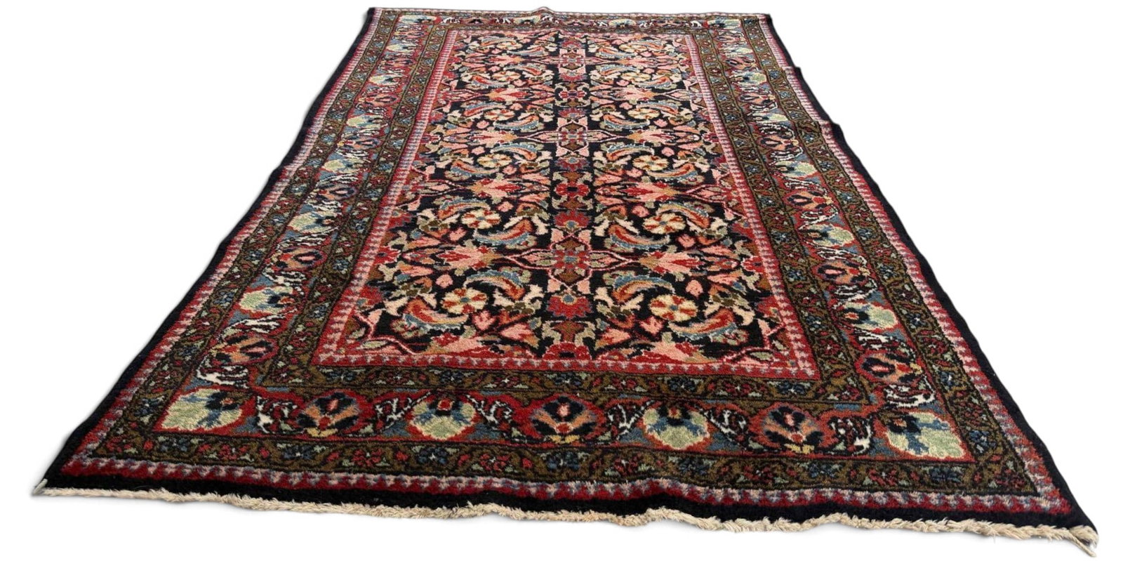 Persian Hamadan Region Floral Rug: Persian Hamadan Region Floral Rug. Hand-knotted wool pile, featuring a dark navy field filled with repeating floral and palmette motifs in red, pink, blue, green, and ivory. The field is framed by a b