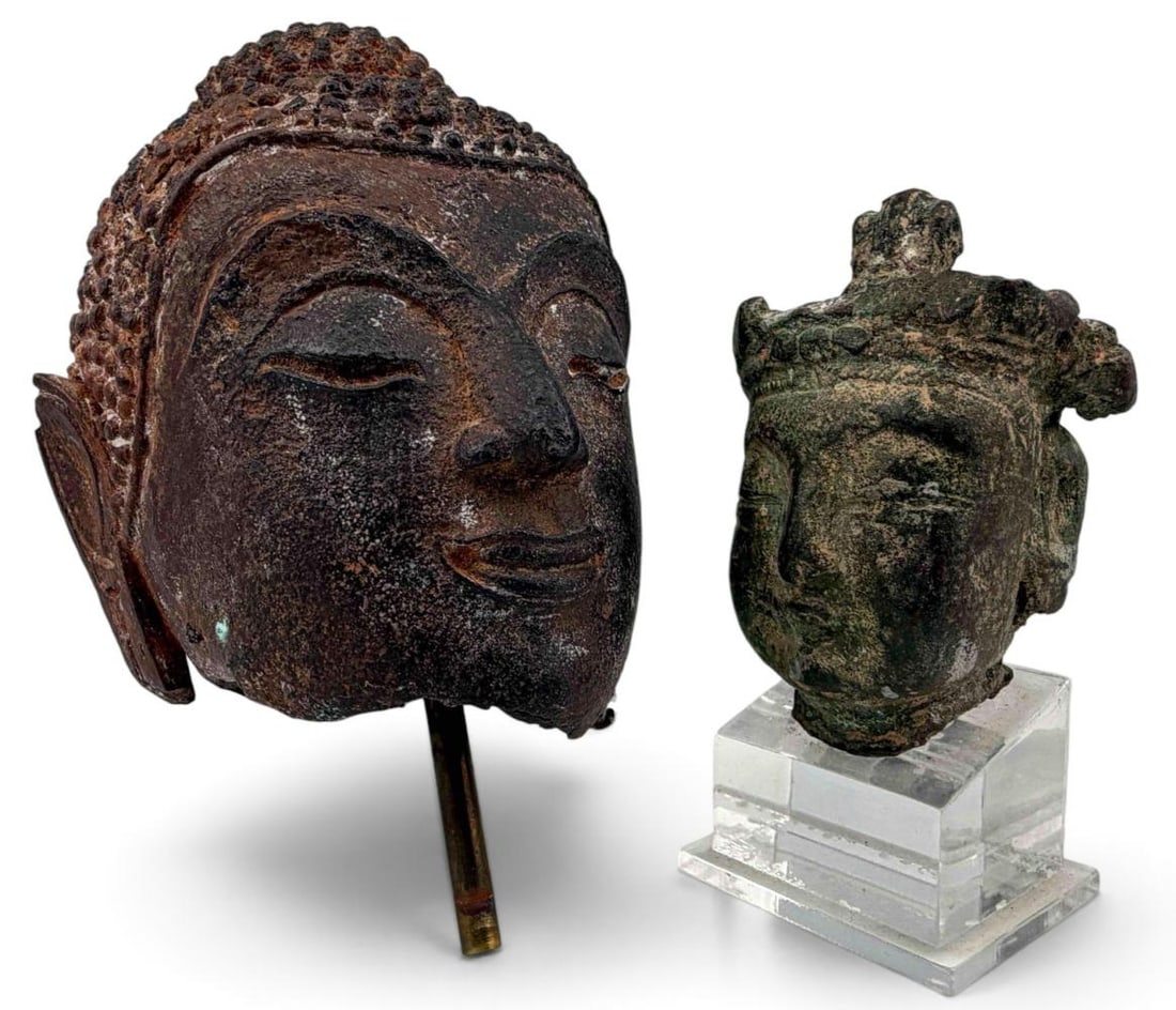 Two Asian Bronze & Iron Buddha Heads: Two Asian Bronze & Iron Buddha Heads. Lager Southeast Asian iron Buddha head approximately 4.0H x 3.17W x 2.80D in. Smaller bronze Buddha head approximately 2.75H x 1.88W x 1.69D in. Height with