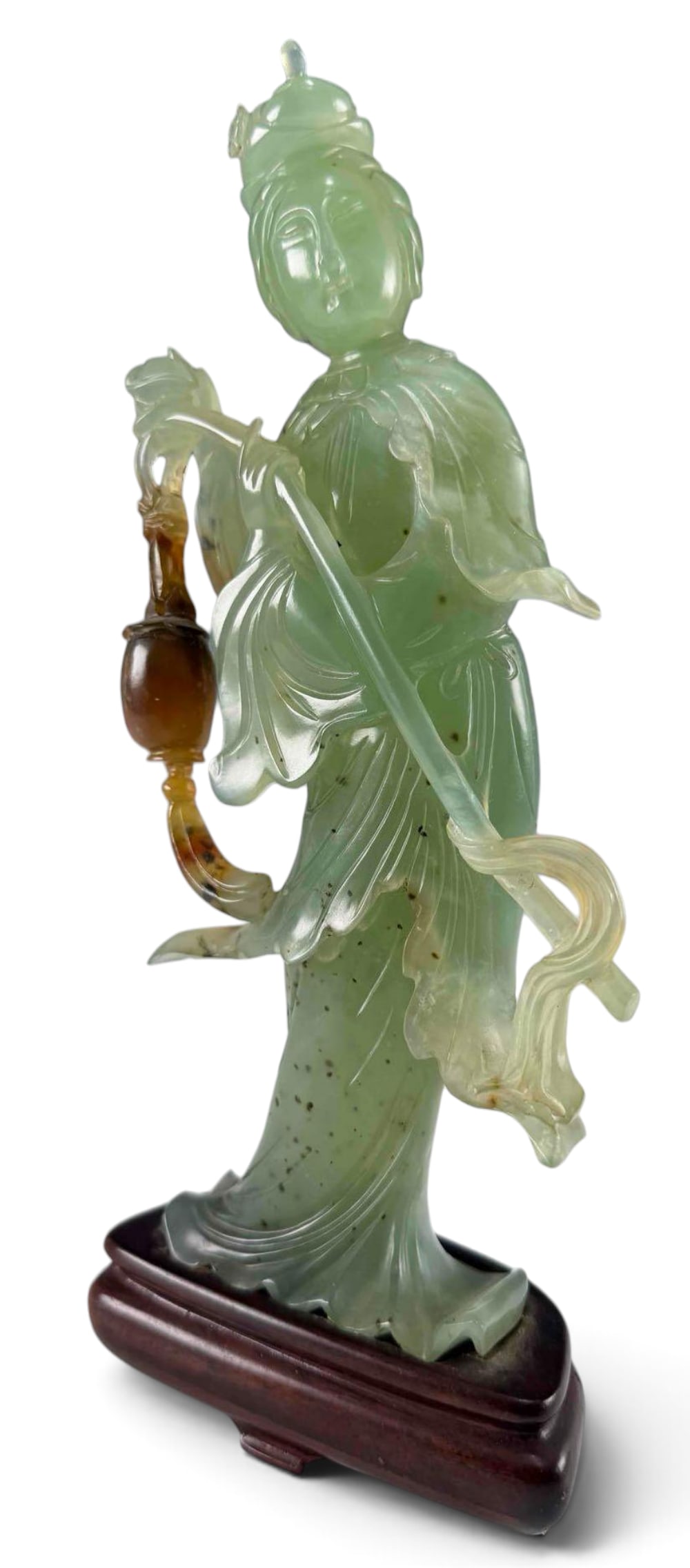 Chinese Carved Green Stone Figure: Carved Serpentine figure of a female Daoist immortal, depicting flowing robes & holding a gourd form, mounted on a fitted dark wood stand. Approximately 9.0L x 4.0W in.
