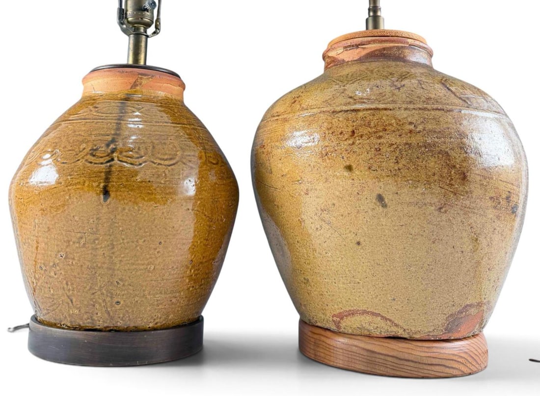 Two Mid Century Art Pottery Table Lamps: Two Mid Century Stoneware Table Lamps. Larger approximately 25.75H x 11.25W in. (Height to top of finial). Smaller approximately 23.0H x 9.25W in. (Height to top of finial).