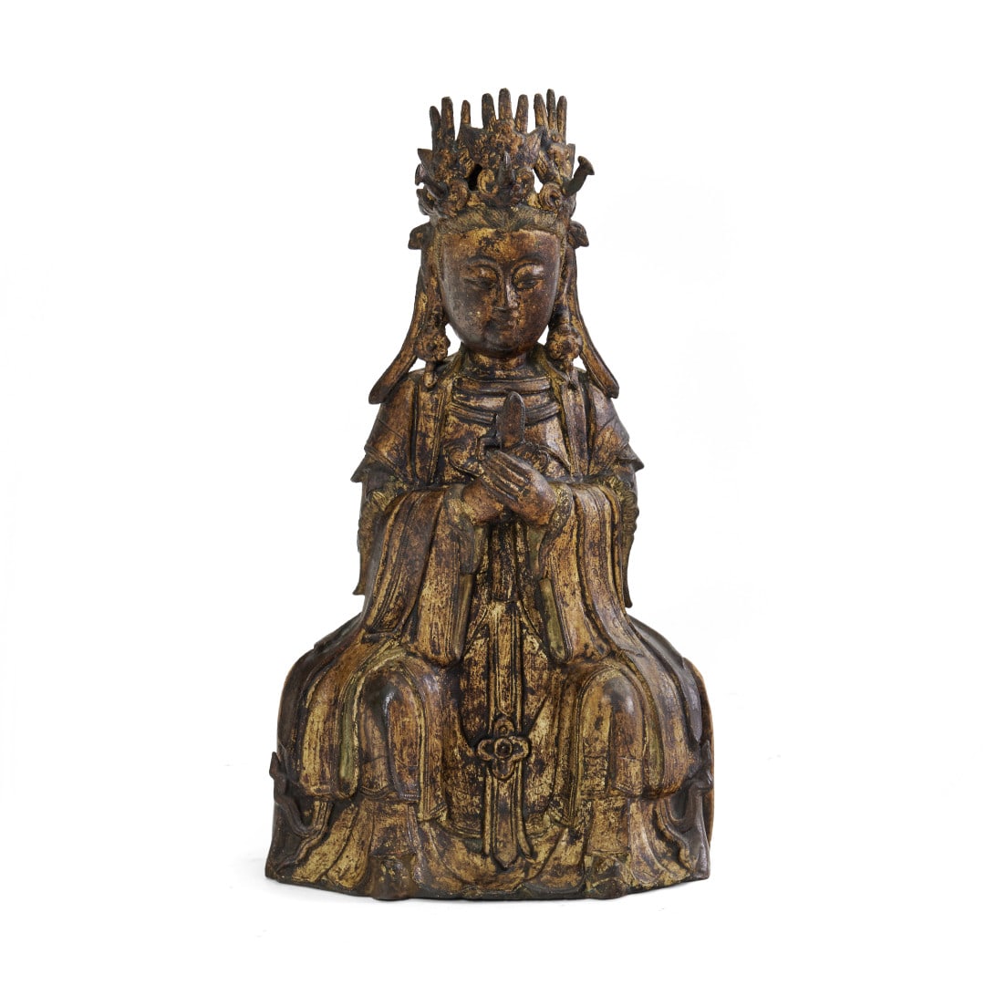 Xiwangmu China, Ming dynasty, 16th-17th century: Gilded bronze, the seated Taoist deity wearing a wide robe with flowing drapery, his hands on his chest holding the hu tablet, his head with a headdress decorated with birds. 15.7 x 9.1 x 4.3 in.