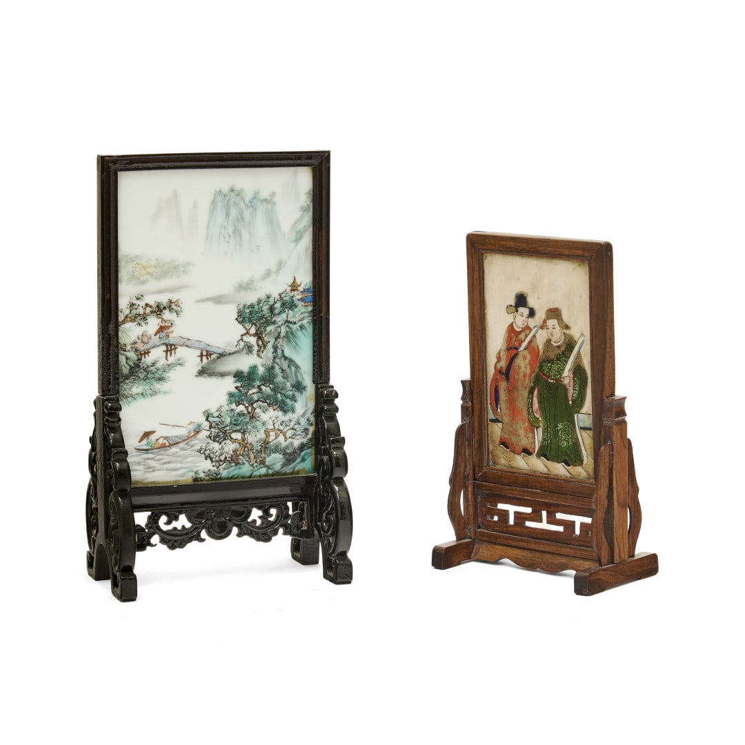 Two small table screens China, 20th century: One with a wooden structure and a porcelain plaque painted with polychrome enamels with a landscape with figures, the back covered in paper with an inscription, the other with a wooden structure and a