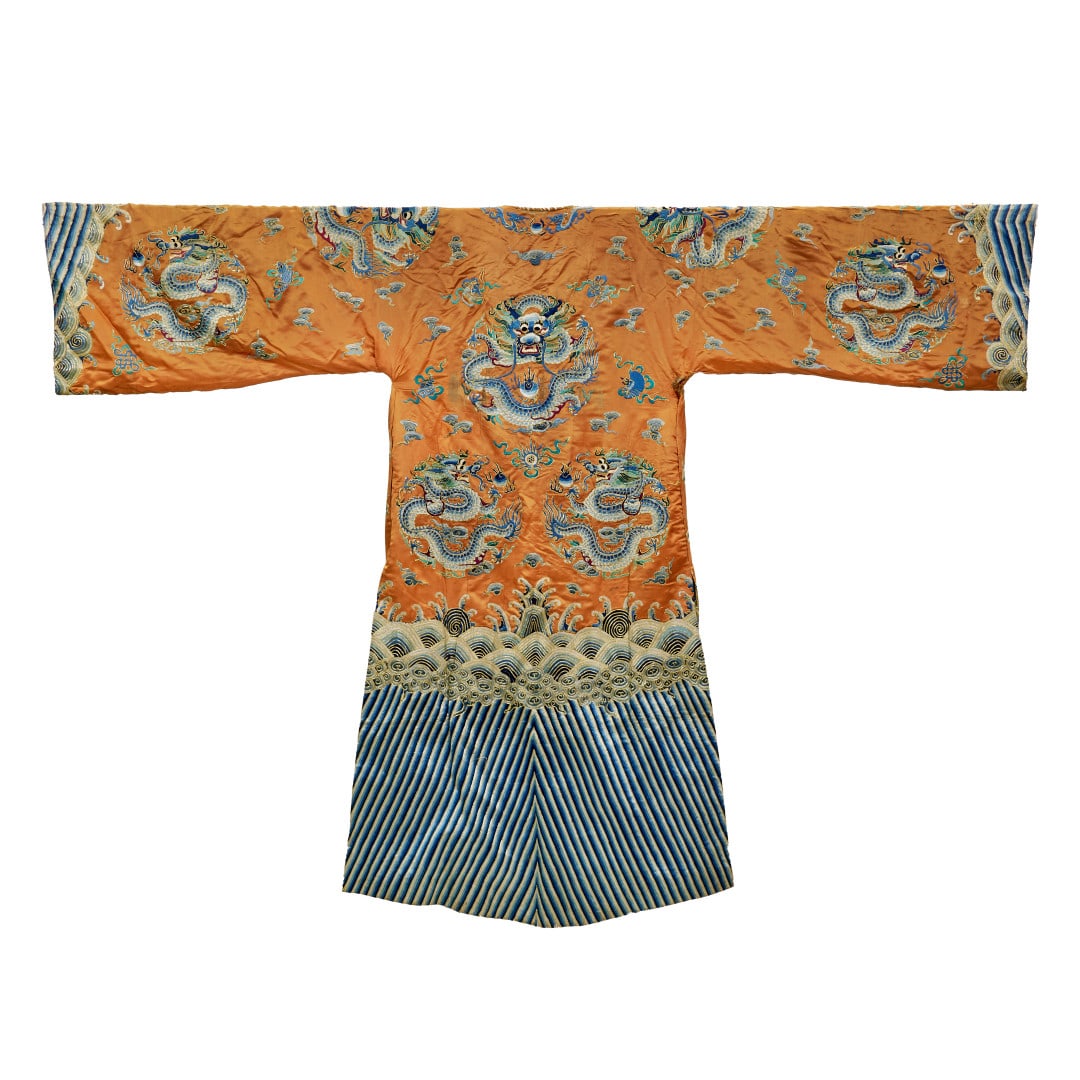 Court robe China, Qing dynasty, 19th century: Apricot ground silk finely embroidered with polychrome and gold threads, decoration of dragons flying amidst clouds and darts, stylised waves and mountain peaks at the bottom. 59.1 x 79.5 in.