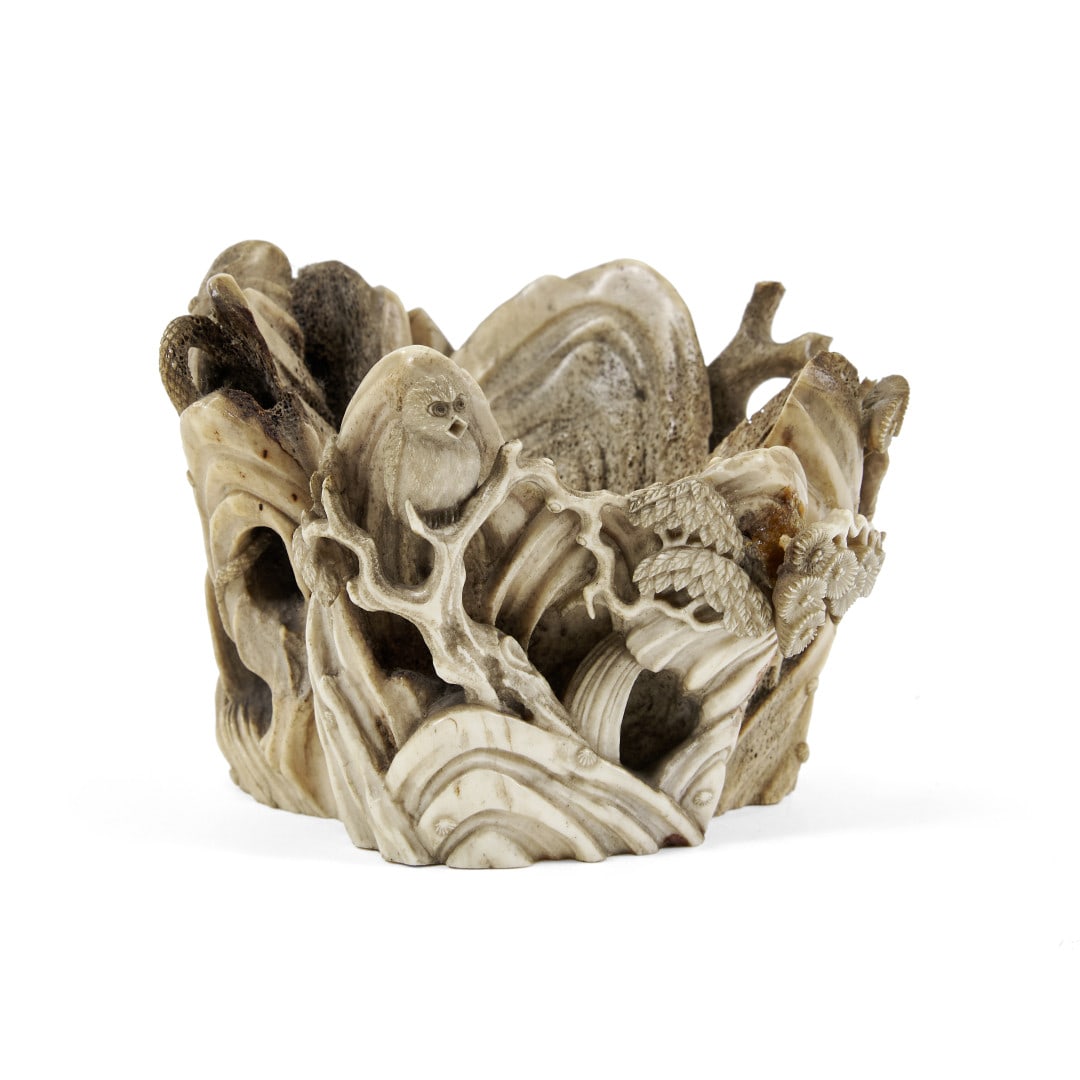 Okimono Japan, Meiji period: Stag antler, carved with a naturalistic composition featuring mountains, pine trees and birds, an owl and a snake. 3.1 x 4.3 in.