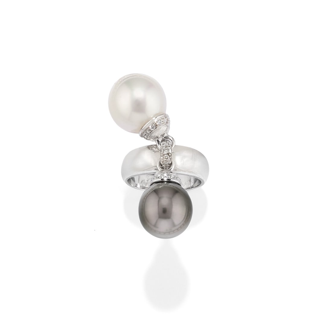 ANELLO IN PERLA BIANCA E GRIGIA - WHITE AND GREY PEARL RING: in oro bianco e diamanti. La perla bianca è di mm 13,50, mentre la grigia di mm 12,60 tenute insieme da un anello di diamanti. Gr 14,90 - nr 12,5 - in white gold and diamonds. The white pearl measure