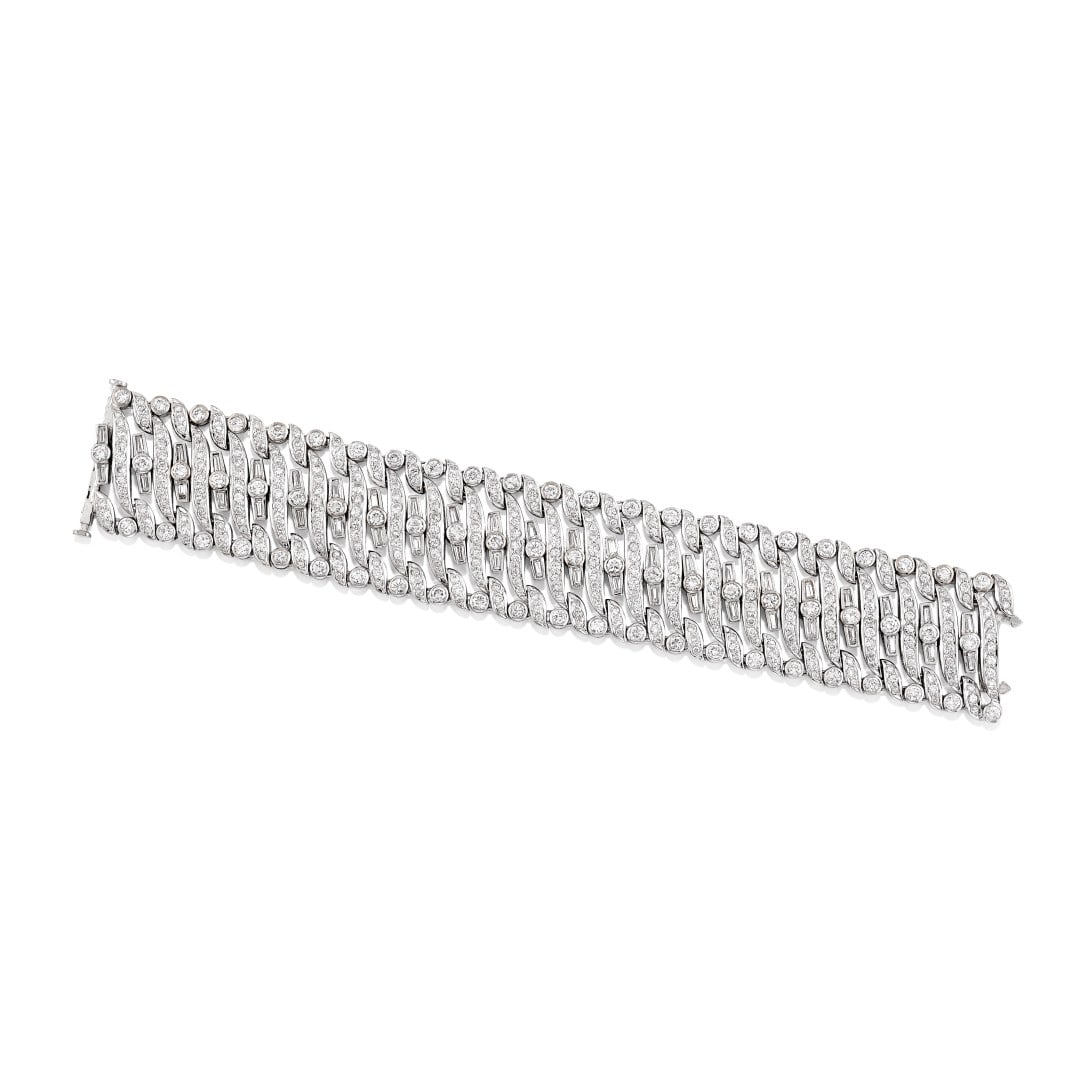 BRACCIALE IN DIAMANTI - DIAMOND BRACELET: in oro bianco a fascia morbida realizzata ad elementi obliqui separati con tre file verticali sfalsate di diamanti taglio rotondo e file orizzontali oblique di diamanti taglio rotondo alternati a tagl