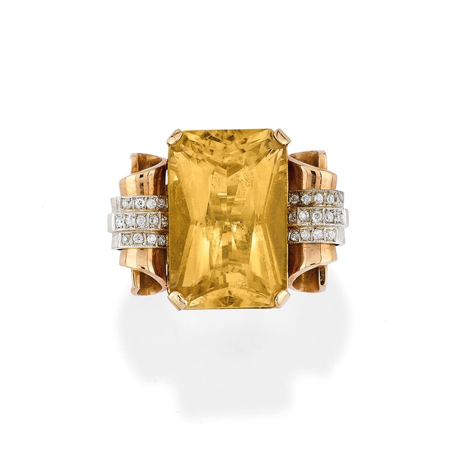 ANELLO IN QUARZO CITRINO E DIAMANTI - CITRINE QUARTZ AND DIAMOND RING: in oro giallo 18 kt con un grande quarzo citrino affiancato da volute impreziosite da diamanti montati in oro bianco 18 kt. Circa 1970. Gr 43,90 - cm 2,90 x 3,80 - nr 14,5 - in 18K yellow gold set wit