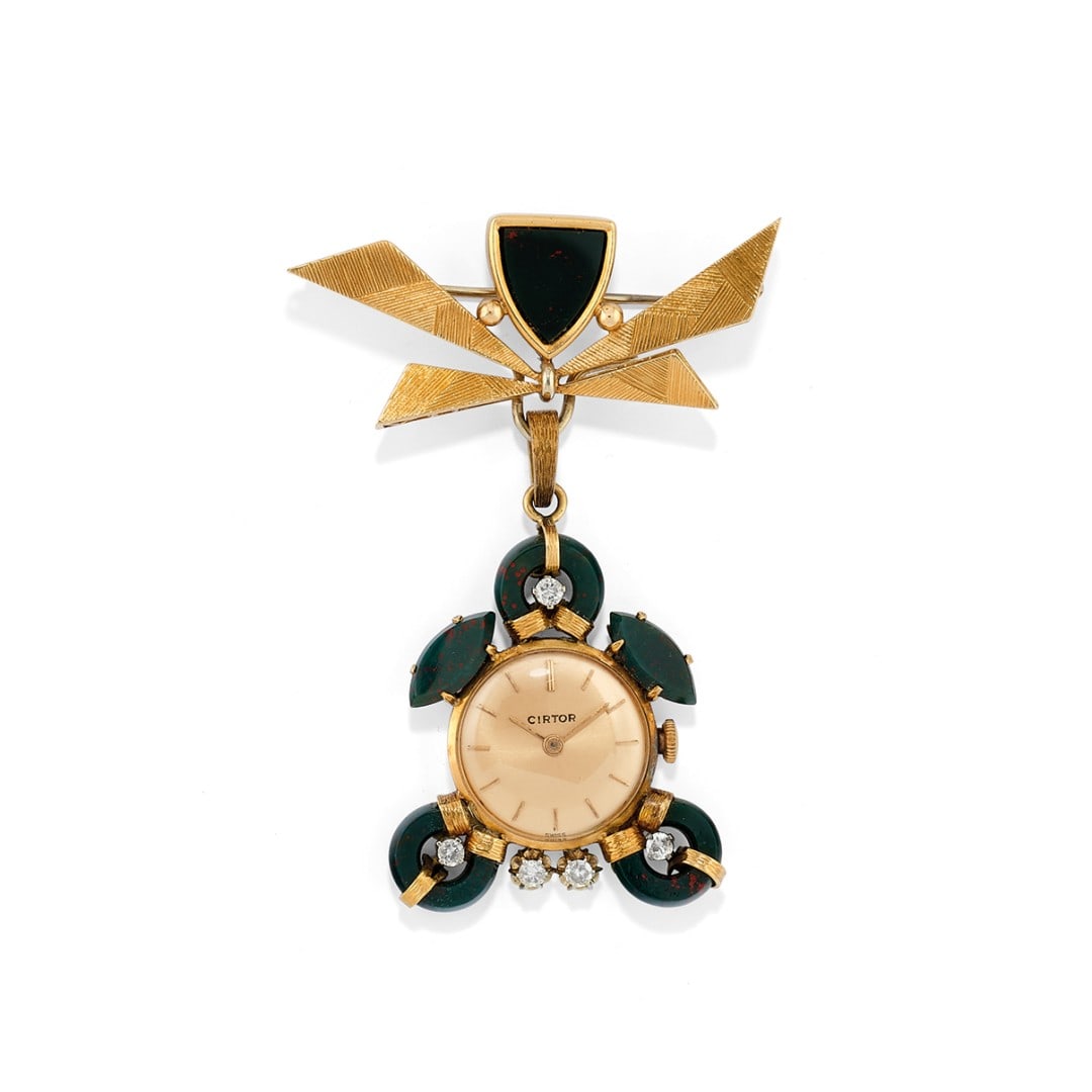SPILLA-OROLOGIO IN DIASPRO SANGUIGNO E DIAMANTI - BLOODSTONE AND DIAMOND BROOCH-WATCH: realizzato da una spilla in oro giallo rigato 18 kt con un diaspro sanguigno a?scudo che trattiene un pendente amovibile con elementi in diaspro sanguigno e cinque diamanti montati in oro bianco 18 kt