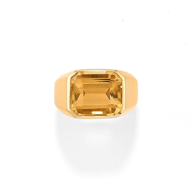 ANELLO IN QUARZO CITRINO - CITRINE QUARTZ RING: in oro giallo 18 kt con gambo a fascia larga che trattiene un quarzo citrino taglio ottagonale ad angoli tronchi di ct 10,00 ca. Circa 1980. Gr 20,20 - cm 1,30 - nr 15 - designed as a large 18K yellow