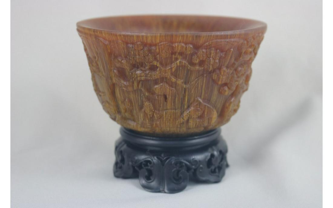 Chinese Horn Bowl: Chinese horn bowl; good brown hue, well carved with figure underneath an pine tree; the whole reserve on an hard wood stand; D: 12 cm, H: 6.5 cm