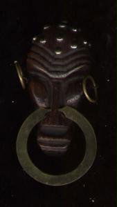 wood brass chrome african mark: In keeping with the Deco designers' fascination with the 'primitif', an African Mask brooch in exotic wood, chrome and brass. The wooden pin itself is 3" long; the brass nose-ring brings the length to