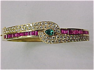 Diamond-Emerald-Ruby Bangle: This spectacular ladies 14kt yellow gold bangle centers upon (1) genuine forest green pearshaped emerald and is surrounded by (34) baguette shaped genuine rubies and (76) round brilliant full cut diam