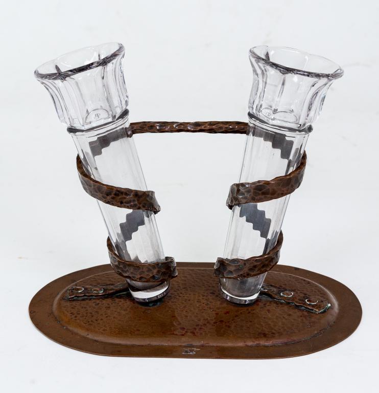 ARTS AND CRAFTS BUD VASE: Nicely executed, Hand hammered Arts and crafts copper double bud vase. Platform base with riveted ribbon styled copper wrapping the fluted glass holders. Anvil stamped makers mark inscribed Yems. Ht.