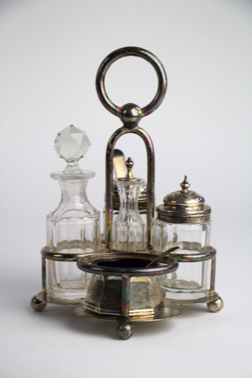 ENGLISH SILVER CONDIMENT SET IN STAND: Stand hallmarked Birmingham 1906 and made by Elkington & Co. Open salter with cobalt lining not original to the piece and has different hallmarks. 2 glass pieces with silver tops have matching hallmar