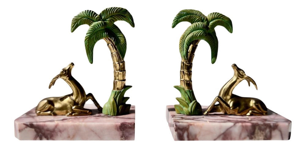 Art Deco Marble Gazelle & Palm Bookends, Set of 2: Hollywood Regency / Palm Beach style. Evoking the glamour of French Art Deco, this figural pair of weighty bookends features reclining gazelles beneath stylized palm trees, cast in gilt metal with han