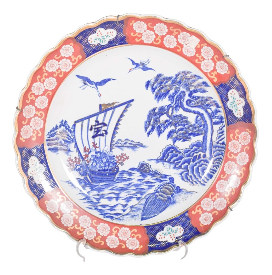 Plate Cut in Porcelain and Polychrome Decoration, 1910: A beautifully crafted cut-out porcelain plate, adorned with vibrant shades of blue, red, white, and gold trim. The front of the plate features a picturesque landscape, with trees, a river, a