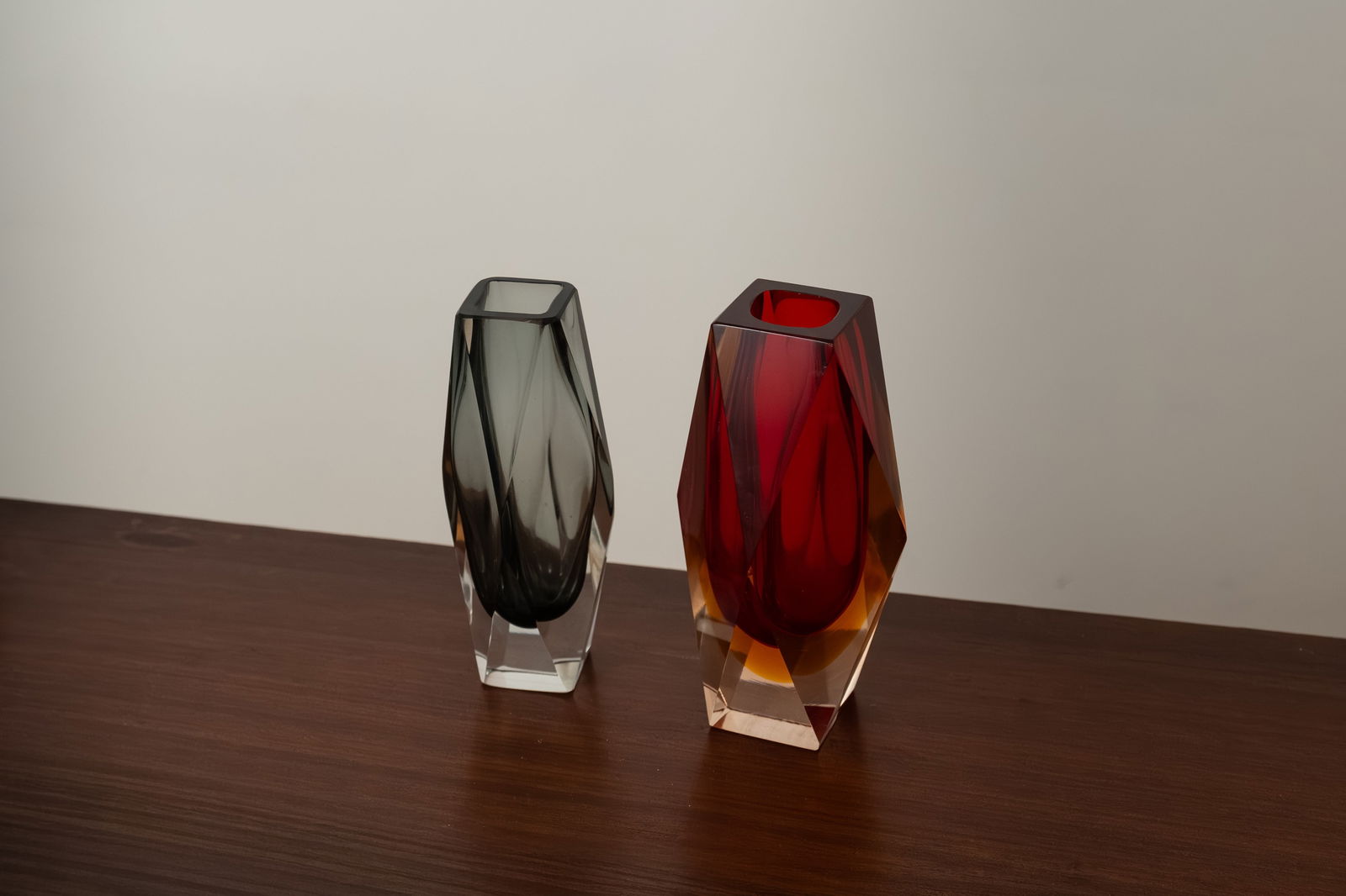 Pair of Murano Sommerso Glass Vases, Italy, 1960s-70s: A pair of Murano vases in the sommerso technique in deep red and smoky gray, a design with geometric motifs, 1960s-70s, Italy. Dimensions: red - height 17, width 8, base 5 cm, gray - 16X7, height 16,