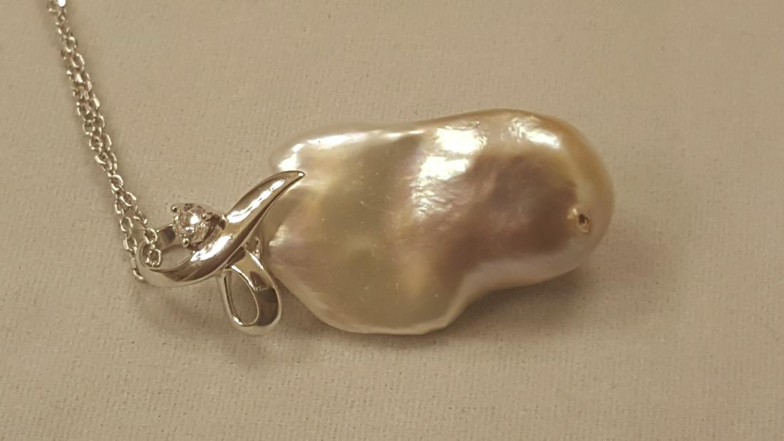 CERTIFIED 8.44 GRAMS MALUKU ISLAND PEARL PENDANT: NATURAL CERTIFIED 8.44 GRAMS MALUKU ISLAND PEARL PENDANT FROM THE MALUKU ISLANDS IN INDONESIA NON TREATED SOUTH SEA BEAUTY.HIGH LUSTER & THICK NACRE .HAS A WHITE TOPAZ ACCENT STONE.MEASURES 36.96 x 16