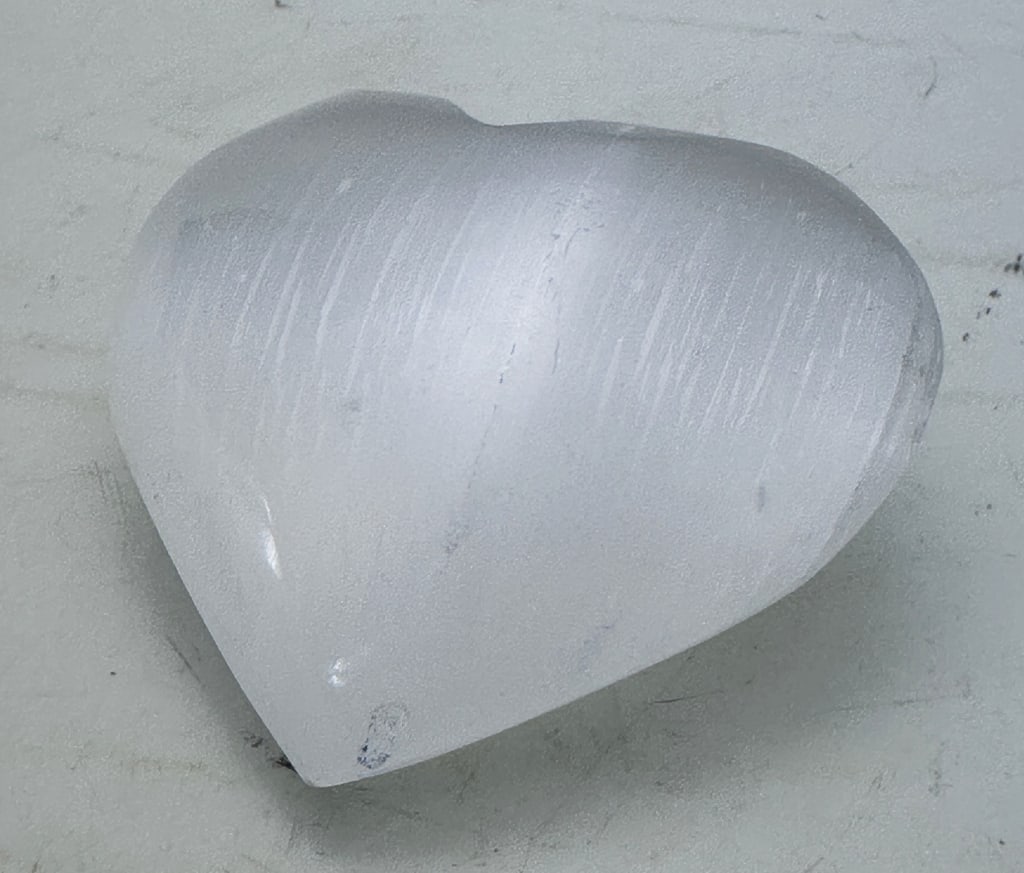 139.15 gram Natural Selenite Carved Heart: Selenite is a mostly clear, transparent variety of the sulfate mineral gypsum. The name selenite is also commonly used for other varieties of gypsum, including satin spar gypsum, desert roses, and